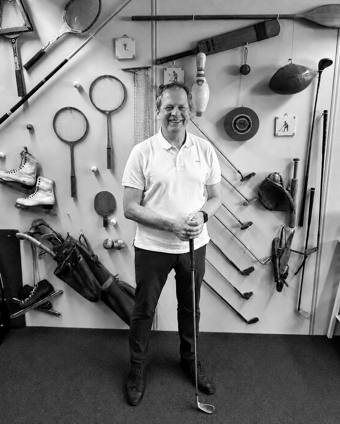 Erik van Wensen holding a hickory iron in front of a wall of vintage sporting gear